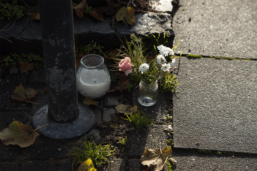 Eine Vase mit Blumen auf einem Bürgersteig.