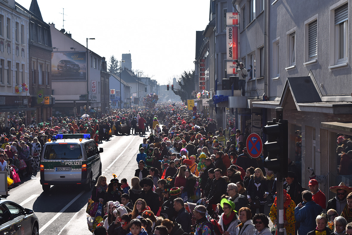 Eine Menschenmenge von ROSENSONNTAGSZUG-Teilnehmern läuft am 19.02.2023 eine Straße in PORZER entlang.